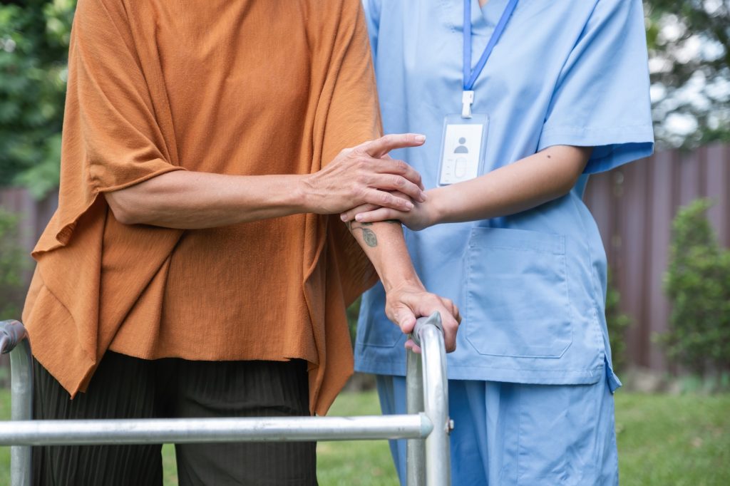 Caregiver Assisting Elderly Woman Outdoors, Focusing on Health and Well-being, Senior Care