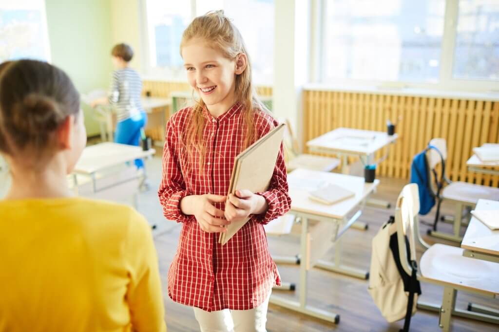 Happy school friends talking in classroom