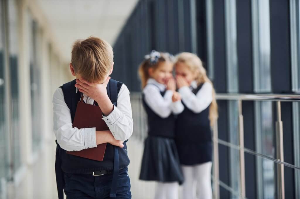 Little boy gets bullied. Conception of harassment. School kids in uniform together in corridor