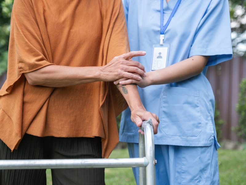 Caregiver Assisting Elderly Woman Outdoors, Focusing on Health and Well-being, Senior Care