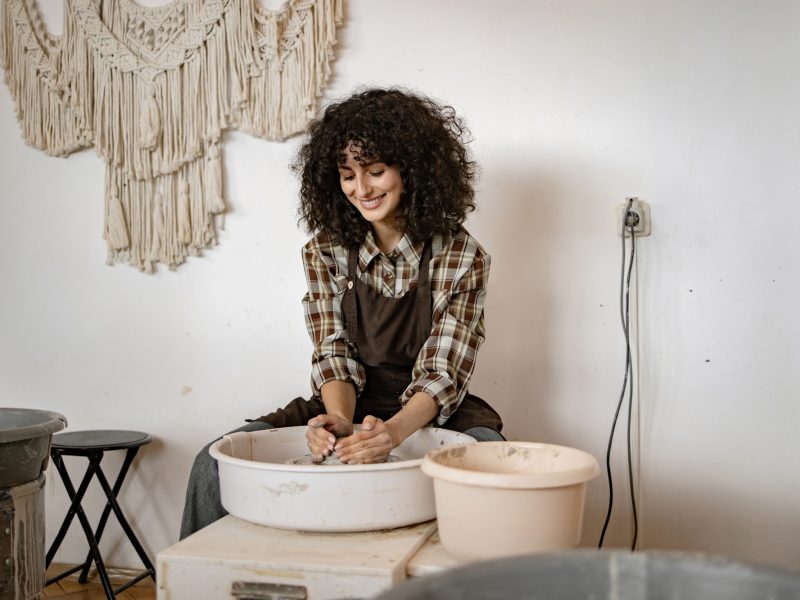 Female artist creating pottery in studio with a smile