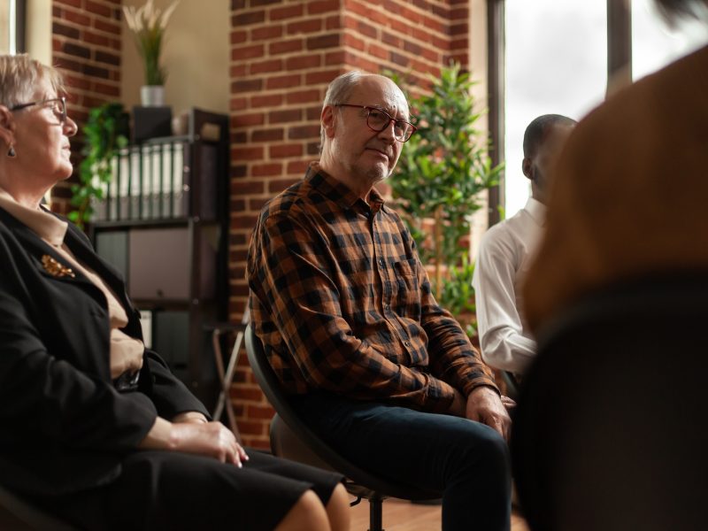 People talking to therapist at aa group therapy meeting, sharing addiction problems
